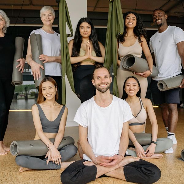 A diverse group of people smiling during a yoga class.