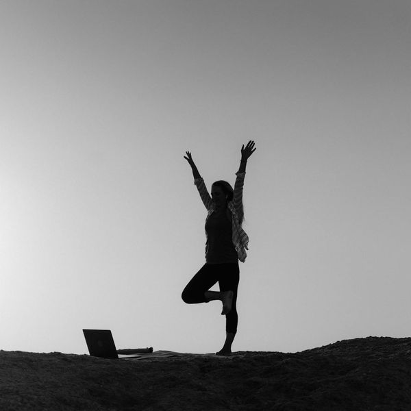 Silhouette of a person in a powerful warrior yoga pose at sunrise.